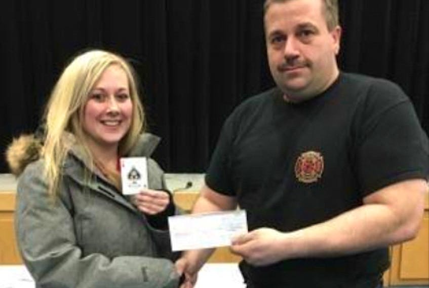 Stacie Genge of Anchor Point happily displays the long-elusive Ace of Spades that earned her nearly $25,000. Straits Fire Department Chief Hank Diamond presents the cheque.