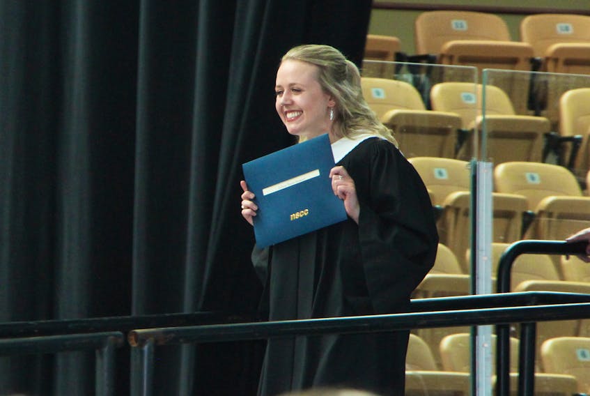 A smiling Julissa Stewart, from Antigonish, holds up her diploma as she exits the stage, during the Nova Scotia Community College Strait Area Campus convocation ceremony, June 7, at the Port Hawkesbury Civic Centre. Stewart earned honours in advanced behavioral interventions.