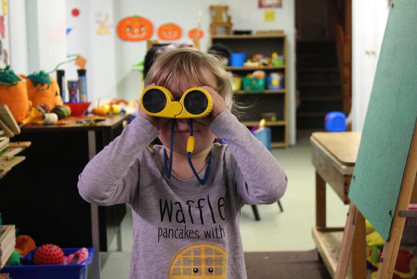 A child looks through a pair of binoculars during play time at a Nova Scotia day care.