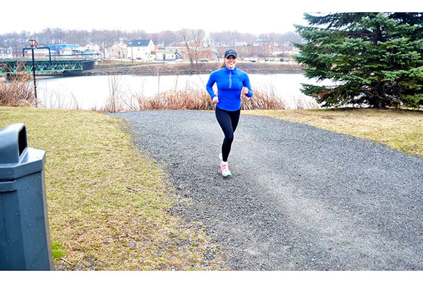 Emily Morton-Fraser approaches a garbage receptacle as she jogs on a trail in New Glasgow.