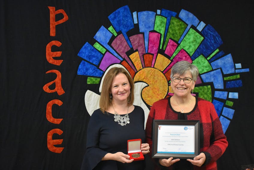 Sarah MacIntosh Wiseman with Pictou County Safe Harbour and Lynne Lockhart with the Trinity United Church pose in front of the Peace Quilt with Safe Harbours awards.
