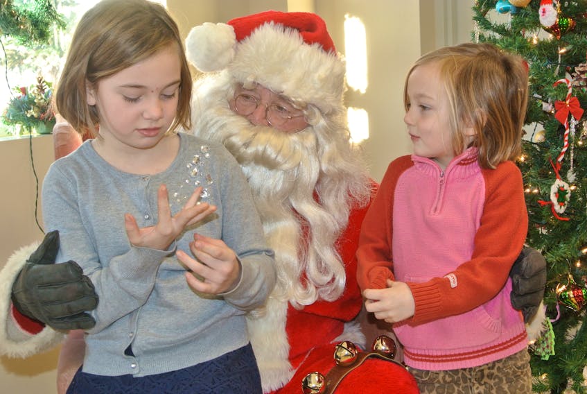 Alexis (left) and Emily McCulloch sit with Santa Claus during the Oxford Lions Club’s Breakfast with Santa on Saturday at the Oxford Fire Department.