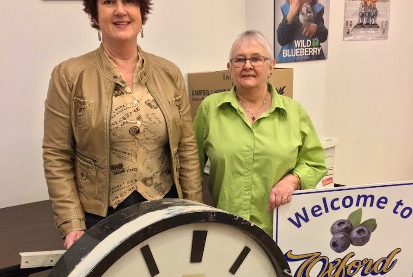 Oxford CAO Rachel Jones (left) and Eleanor Crowley of the Oxford Historical Society stand beside the clock that was located on the former post office and town hall building. It will be brought out of storage and placed in the arena in the spring with a plaque explaining its history.