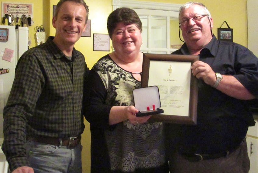 Senator David Wells presenting the medal to Olive and Keith Barnes of English Harbour.