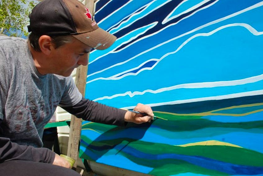 Reilly Fitzgerald painting one of the murals for the Town of Clarenville.