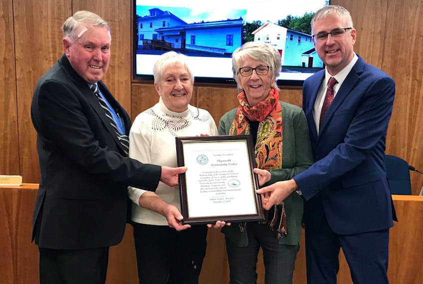 Warden Robert Parker, left, and District 11 Coun. Andy Thompson presents Ruth Thompson and Janet MacDonald with a plaque of recognition in honour of the Plymouth Community Center's recent success in installing solar panels on its building.