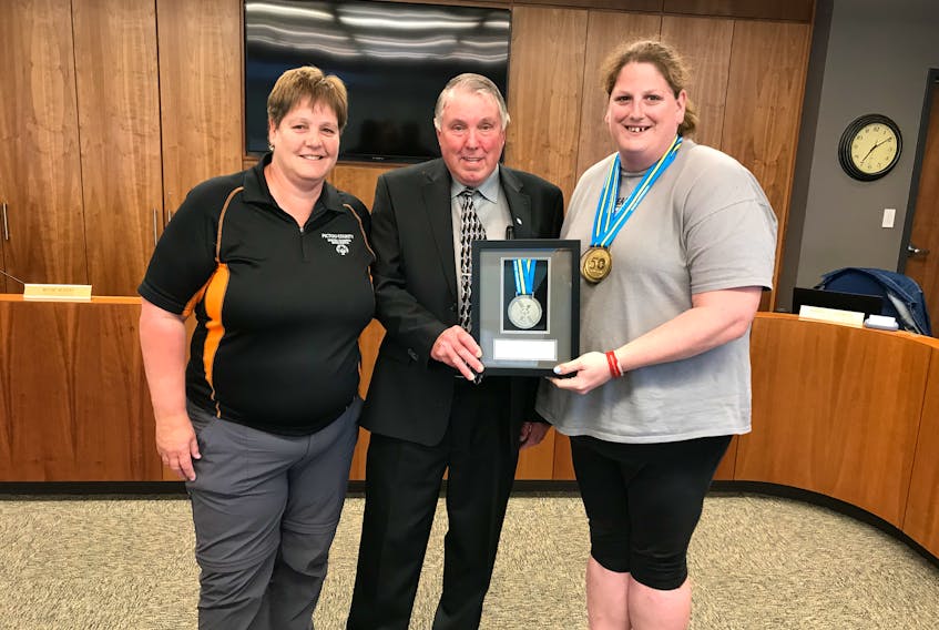 Cathy Mason, left, regional coordinator for Special Olympics Pictou County,  and Stacey Saunders, a national gold and silver medalist for Special Olympics, present Municipality of Pictou County Warden Robert Parker with a silver medal as a thank you for the County’s financial support of the national games held in Antigonish in 2018.