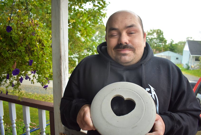 Outside his home in the town of Pictou, Chris Knowles holds one of the projects he and ten other people with visual impairment made at the NSCAD Community studio in New Glasgow.