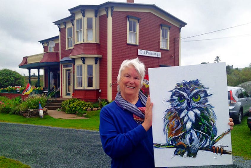 Donna Maguire holds an owl painting. She's donated a similar painting to help raise money for a new shelter for feral cats in New Glasgow.
