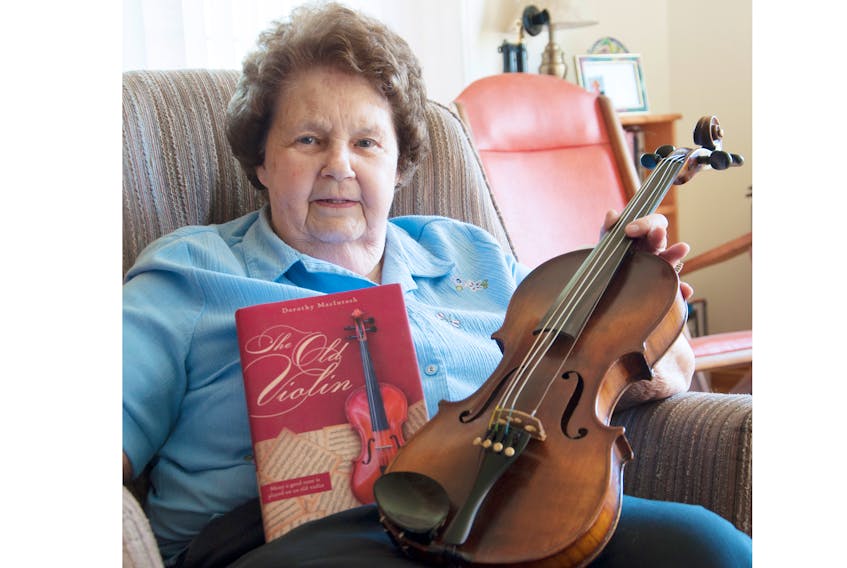 Dorothy MacIntosh holds an old violin that inspired her to write her first novel called The Old Violin. She is 86.