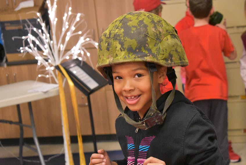 New Glasgow Academy grade 3 student Kylie Dunn tries on a Canadian Armed Forced combat helmet on display at New Glasgow Academy. The Pictou County Military Museum, donated this and many more artifacts for the school's Remembrance Day event.