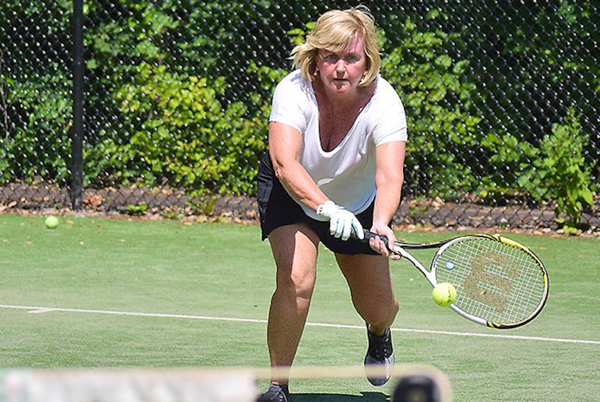 Angela Curry reaches to hit a backhand during a game of doubles at the west side courts on Aug. 2