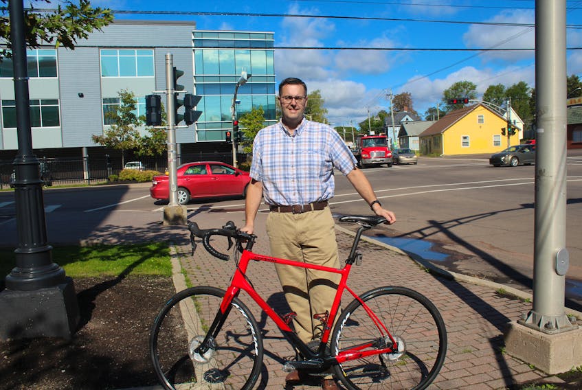 Andrew Burt gets ready to rack his bike on Kent Street where he works. Burt is one of many advocates for a new bike path from the Cornwall Terry Fox Centre to the North River Causeway.
