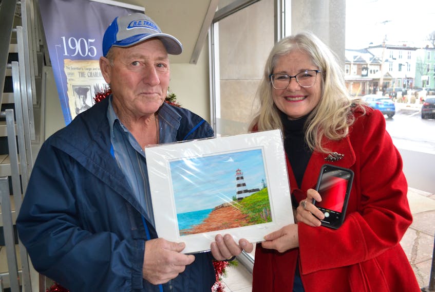 John Arsenault receives a print of the West Point Lighthouse from P.E.I. artist Ann Clow. It’s a thank-you gift after he found her brand-new iPhone in the Charlottetown Mall parking lot.