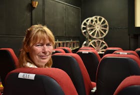 Carol Horne, president of the Charlottetown Film Society, sits in one of the new designated seats inside City Cinema on Sunday. The marked seats ensure patrons are socially distanced inside the theatre.