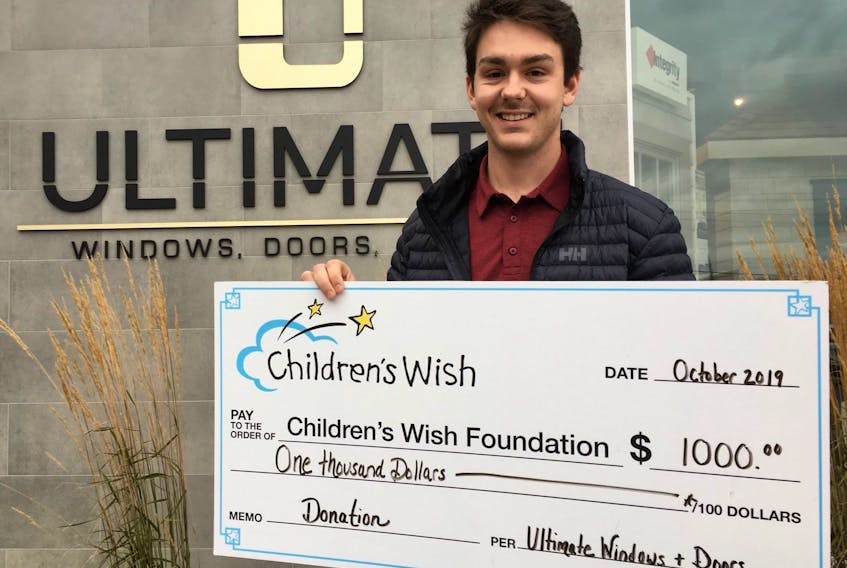 Employee Alex Hughes presents a cheque to the Children's Wish Foundation on behalf of Ultimate Windows and Doors.