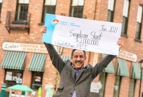 Linda's Coffee Shop owner Seyedazim Sharif holds up a novelty $2 million cheque after winning big on a scratch ticket.