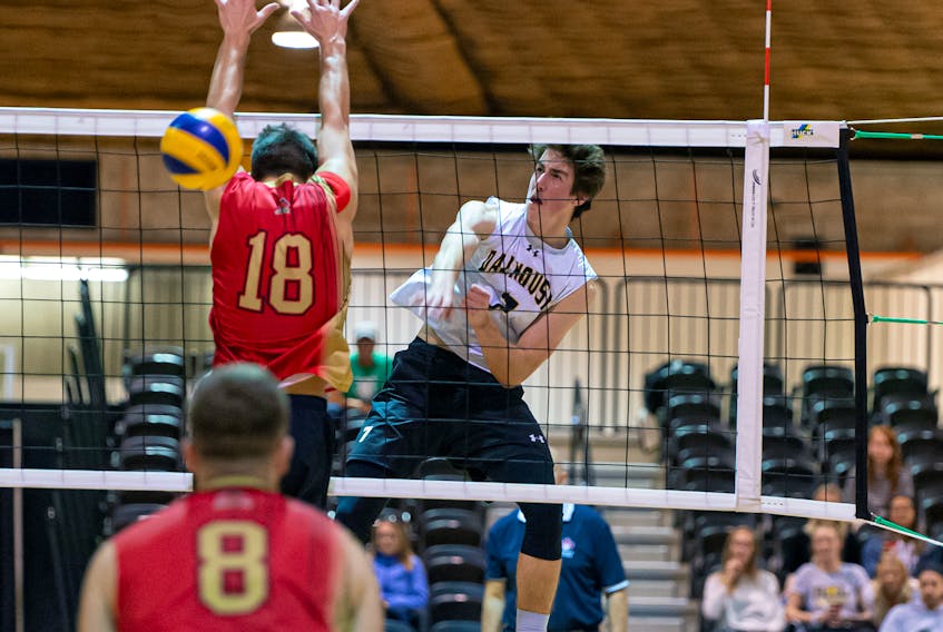 Dalhousie Tigers left side hitter Ethan Boyd, right, hammers a hit past the block. - Trevor MacMillan Photography