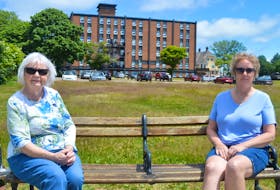 Arlene Mamye, left, and Louise Aalders lead an ad-hoc committee representing the residents of the 43-unit apartment building Renaissance Place, pictured in the background. They’re upset they haven’t been consulted about the proposed 99-unit apartment building that will be going up on the green space just behind them.