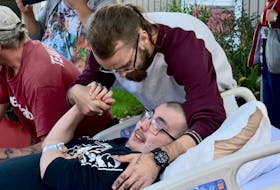 Jesse Crockett embraces his friend Will MacLeod on Sunday as more than 200 cars started to drive by palliative care at the Queen Elizabeth Hospital. Crockett, with the help of Austin Mackinnon, organized the cruise to support his dying friend who loves cars.