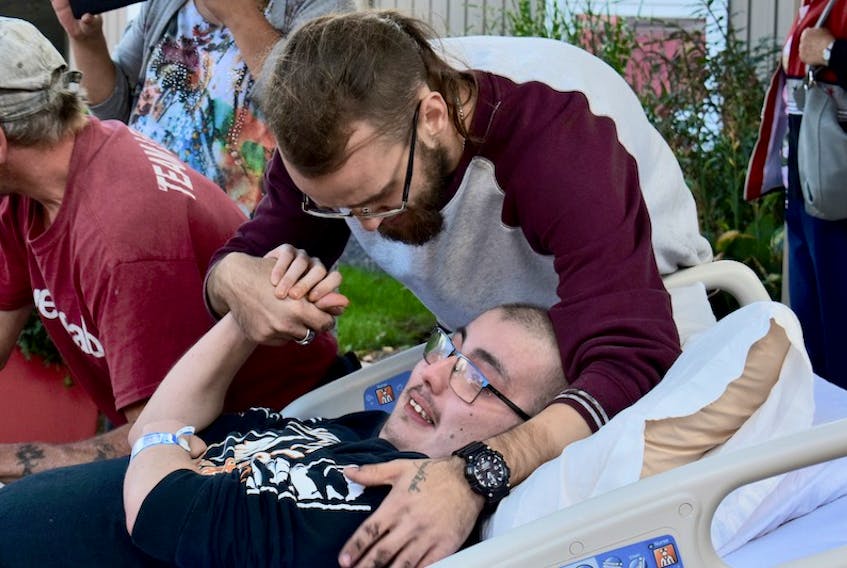 Jesse Crockett embraces his friend Will MacLeod on Sunday as more than 200 cars started to drive by palliative care at the Queen Elizabeth Hospital. Crockett, with the help of Austin Mackinnon, organized the cruise to support his dying friend who loves cars.