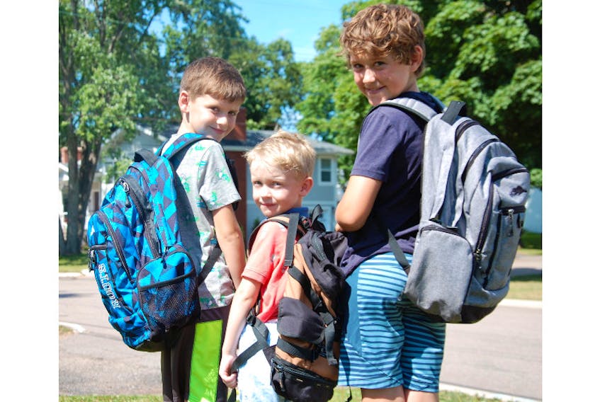 Elliot Hillier, 5, middle, and his brothers, Lachlan, right, and Patrick, pose in their backpacks Wednesday after the government announced plans for safely returning P.E.I. students to full-time in-class learning on Sept. 8. Physical distancing, directional signage and increased hand-washing and sanitizing stations are among the safety measures being imposed.