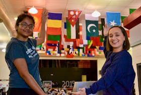 Students Shreya Singh, left, and Payton Alexander show off the flags of more than 50 countries representing the many cultures at the school hanging from the cafeteria ceiling at Colonel Gray High School in Charlottetown.