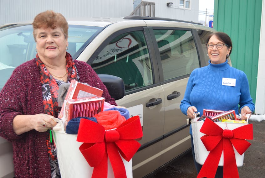Betty Begg-Brooks, left, who runs the not-for-profit organization Gifts From the Heart store in Charlottetown, and Debbie Reid, one of the 71 volunteers at the store, stand in front of a 2014 Dodge Caravan the provincial government donated to the organization on Wednesday. They are holding hampers filled with items available at the location. - Dave Stewart