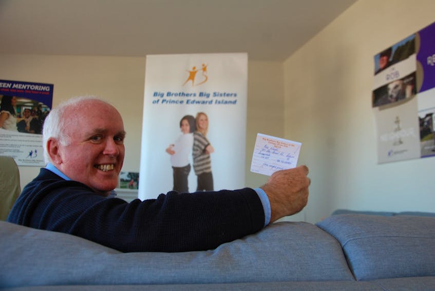 Myron Yates, executive director of Big Brothers Big Sisters of P.E.I., holds the winning ticket for the dream cottage. Alex Waugh of Wilmot Valley is the 2019 winner.
