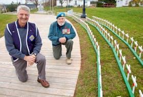 James Donnelly, grand knight of the Knights of Columbus (K of C) Father McNeill Council 9025, left, and K of C member Simon Lemay pose by the impressive display of wooden crosses that pay tribute to 420 late veterans buried in the North Rustico area.