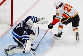 Winnipeg Jets’ goaltender Connor Hellebuyck makes a save on Calgary Flames’ forward Dillon Duke during the second period of Thursday’s Western Conference qualifications series. Calgary eliminated Winnipeg with a 4-0 victory to take the series 3-1.