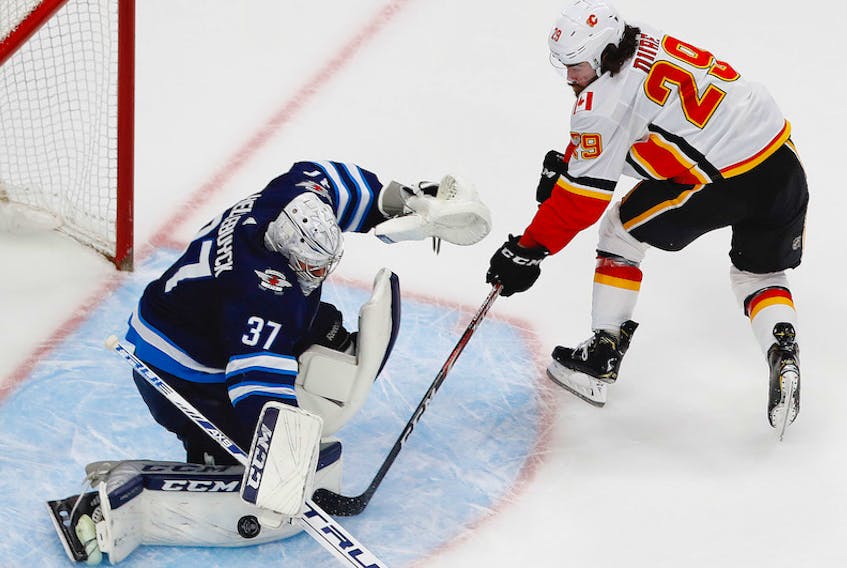 Winnipeg Jets’ goaltender Connor Hellebuyck makes a save on Calgary Flames’ forward Dillon Duke during the second period of Thursday’s Western Conference qualifications series. Calgary eliminated Winnipeg with a 4-0 victory to take the series 3-1.