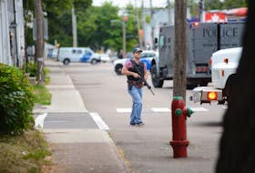An armed Charlottetown police officer walks through the scene of a standoff after a report of someone seeing a man carrying a gun and a sword on Aug. 21, 2020.
