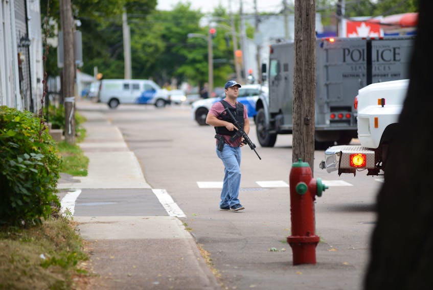 An armed Charlottetown police officer walks through the scene of a standoff after a report of someone seeing a man carrying a gun and a sword on Aug. 21, 2020.