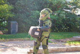 A member of the explosive removal unit from Halifax carries a suspicious device in a secure container from a Charlottetown home Tuesday. The removal unit took the device, which looked like a possible small pipe bomb, back to Halifax to be detonated and analyzed.