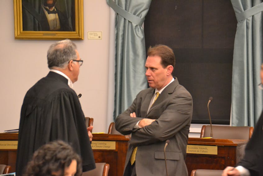 Health Minister James Aylward, right, speaks with Speaker Colin LaVie. Aylward faced a volley of questions about health-care shortages on P.E.I. in the legislature on Wednesday.