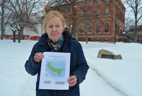 Anti-poverty activist Mary Boyd holds up the 2019 report on child poverty in P.E.I. outside the Coles Building in Charlottetown.