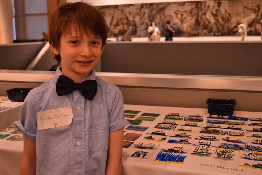 Artist Tristan MacGregor, 7, stands with his collection of shipwreck trading cards.