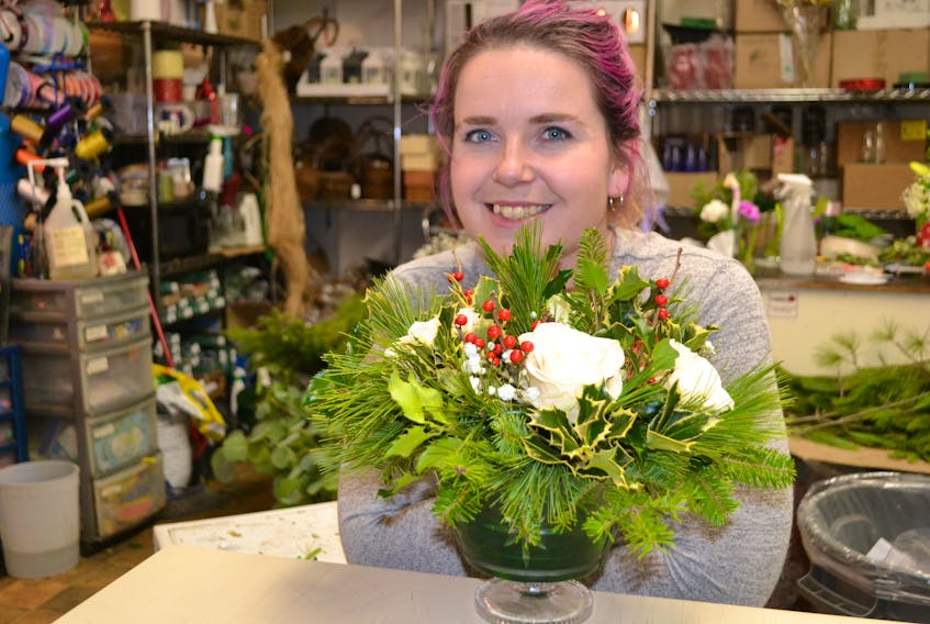 Mary Kate Stuart, floral designer at Hearts and Flowers, shows an arrangement she has made for a customer who recycles this bowl each year. Recycling containers is one of the ways to reduce one's carbon footprint. - Sally Cole