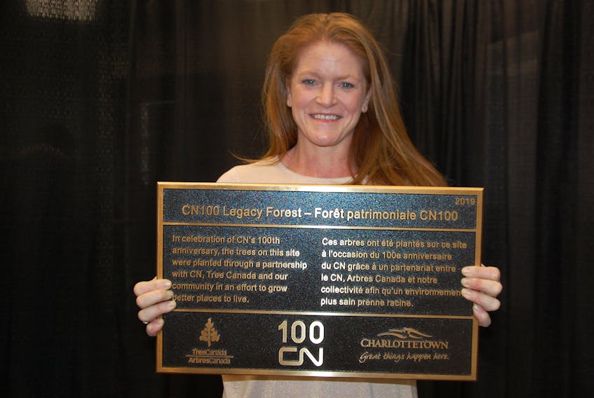 Heidi Hyndman, president of Upton Farm Trust, holds a plaque that commemorates a gift from CN of 100 trees that have been planted at Upton Farmlands.
