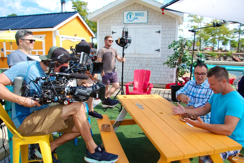 A crew from the Food Network film John Catucci, left, the host of the show "Big Food Bucket List", chatting with Grant Pye of Charlottetown about the classic poutine served at The Chip Shack.