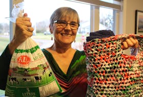 Anna Farquhar showcases a standard milk bag, left, and one of the tote bags she turns them into and sells for charity. Each tote bag takes about 60 milk bags, but Farquhara is struggling to find the raw materials since moving to P.E.I., she said. Daniel Brown/The Guardian.