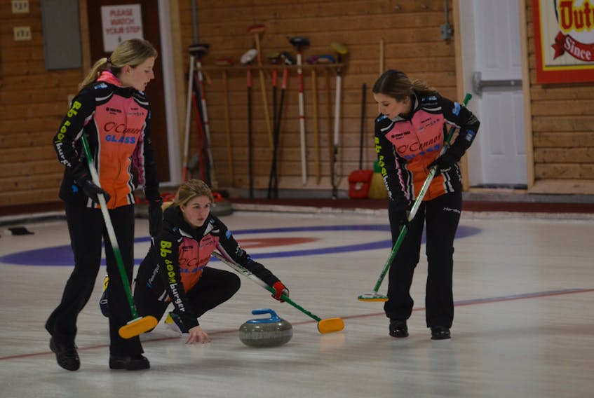 Lead Rachel O’Connor, right, and second stone Kristie Rogers prepare to sweep for skip Lauren Ferguson during the Pepsi provincial junior curling championships at the Crapaud Community Curling Club on Dec. 28.