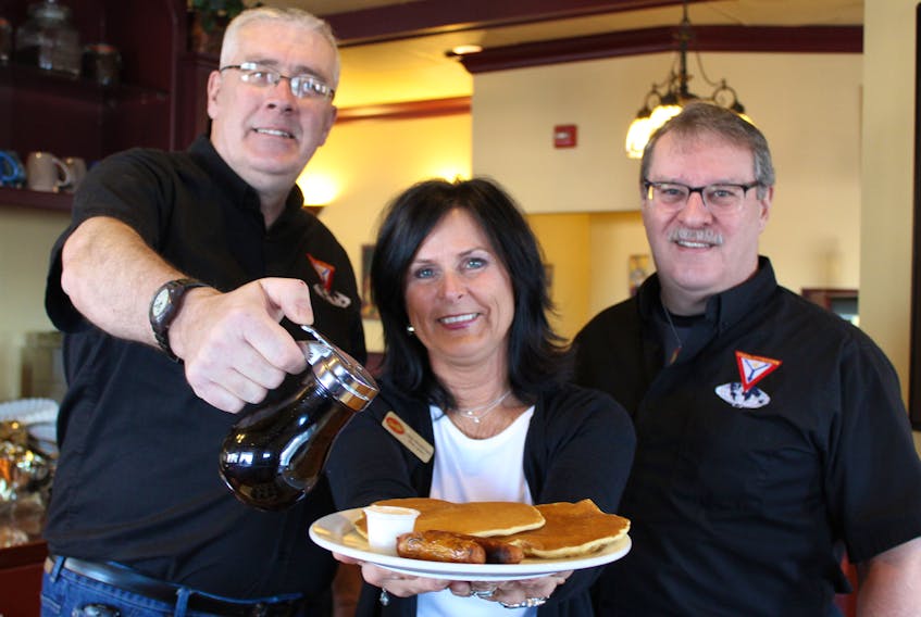 Cindy MacDonald, owner of Smitty's Family Restaurant on University Ave, offers a plate of pancakes alongside the Charlottetown Y's Men president Blair Cutcliffe, right, and club chairperson Allen Veale. Smitty's will be hosting its 39th annual pancake breakfast fundraiser for the Y's Men's projects on Feb. 25.