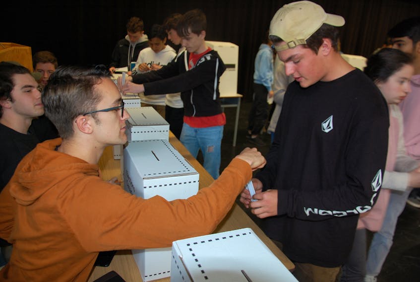 Reece Hunter, 17, left, mans a ballot box during a mock election held at Charlottetown Rural High School Friday, giving students a taste of the democratic process. Jim Day/THE GUARDIAN