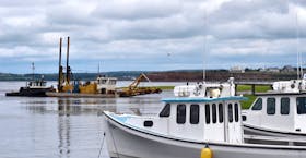 Fishing boats, safely moored at Malpeque harbour, are shown not far from a dredge that is used to try to keep the harbour channel clear so fishers can enter and exit without incident. Plans were recently approved to move ahead with creating a new harbour at Cabot Shores.