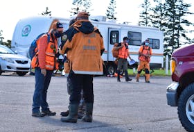 Volunteers with P.E.I. Ground Search and Rescue (GSAR) discuss a search route Sunday before heading off to continue their efforts to find 17-year-olds Alex Hutchinson and Ethan Reilly, missing since their dory capsized Wednesday near Fox Island. GSAR is co-ordinating with the RCMP on the efforts while residents continue to help search the waters nearby in fishing boats and personal watercrafts.