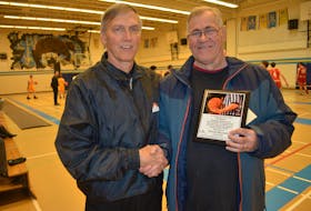 West Prince basketball referee Peter Bolo, left, presents his longtime friend and officiating partner, Harvey Mazerolle, with a plaque in recognizing his 40-plus years as an official in the sport. Mazerolle retired following the 2019 season.