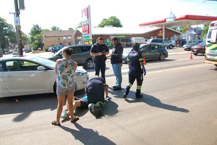 A paramedic tends to a woman who was struck by a motorist while she was attempting to cross the road at the intersection of Euston Street and Weymouth Street in Charlottetown Aug. 21.