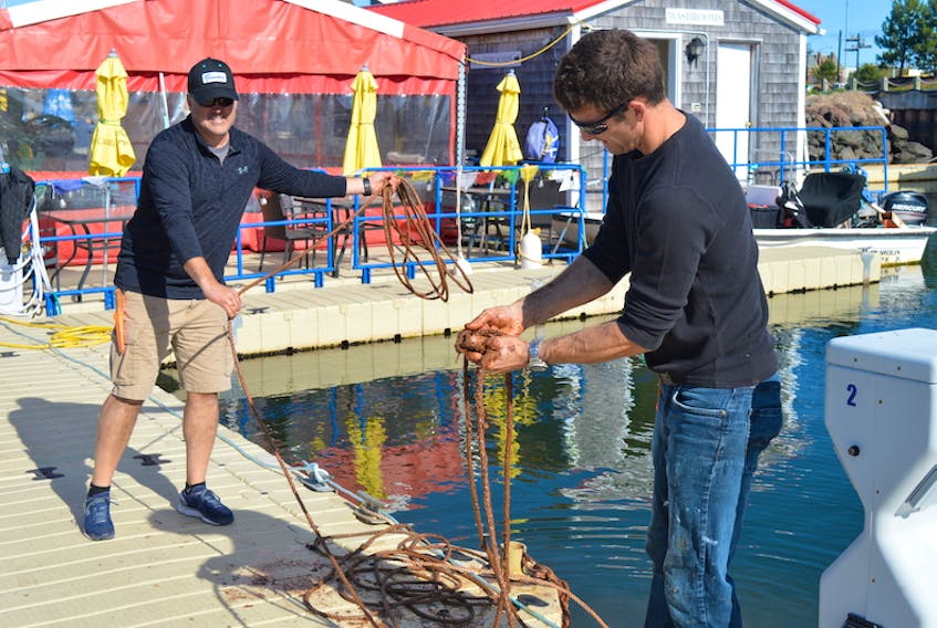 Mike Hunter, left, and Dave Morley work with ropes on Monday that will help secure the anchor system for the floating dock at the Charlottetown Marina.